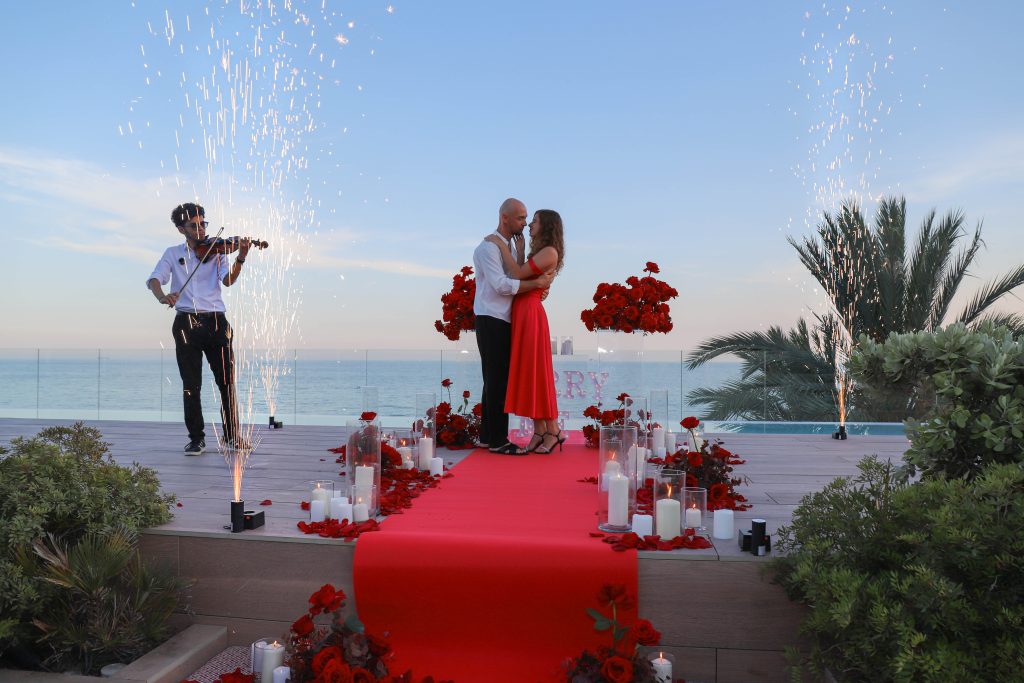 Romantic surprise proposal at sunset on a luxury Barcelona beach.