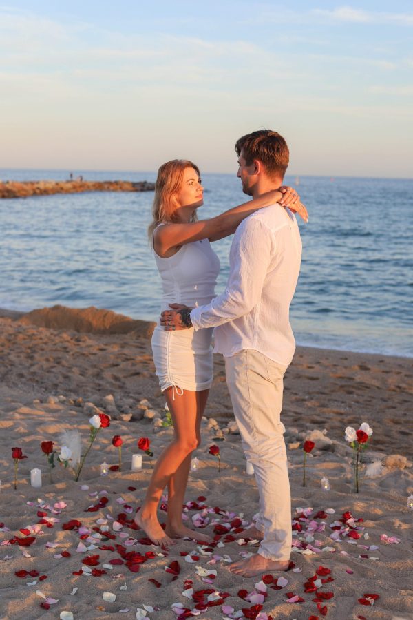 Man kneeling on the sand proposing at sunset, Barcelona beach