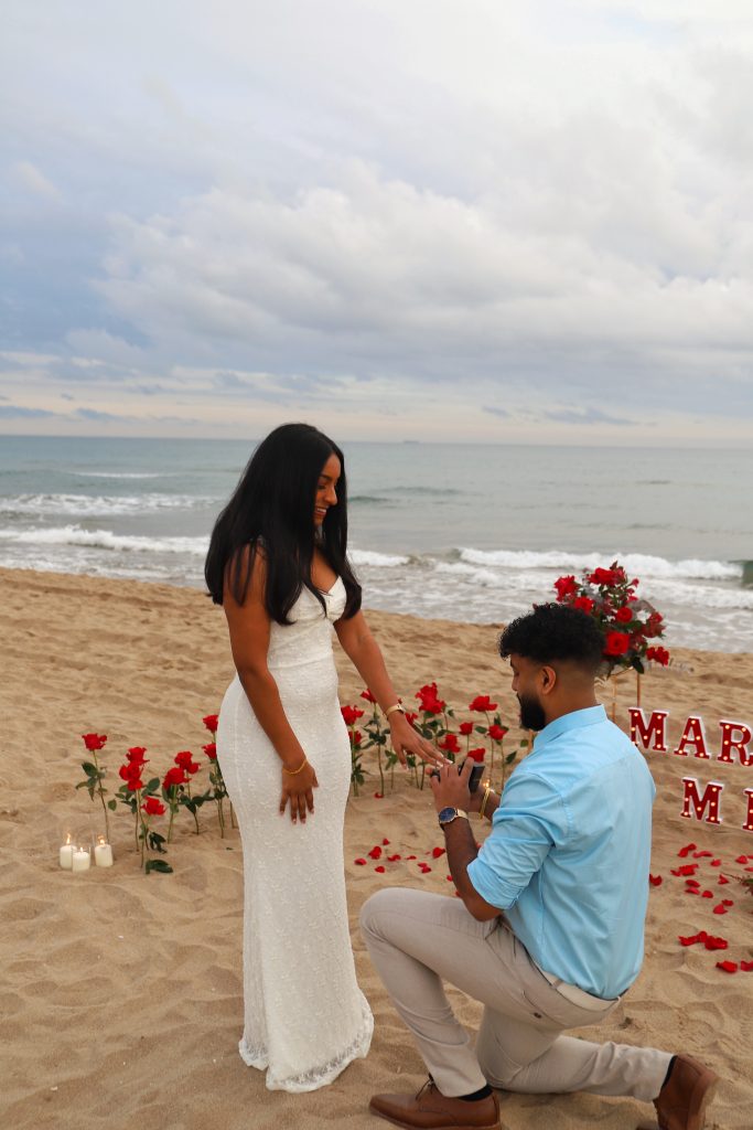 Surprise marriage proposal on Barcelona beach with candles and roses